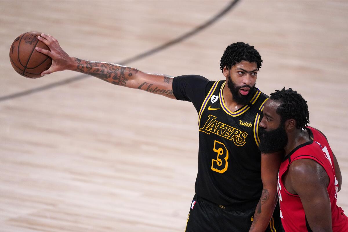 Lakers' Anthony Davis holds the ball as Rockets' James Harden defends against him in a Sept. 6 playoff game.