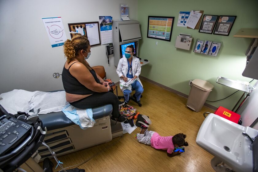ALBUQUERQUE, NM - JUNE 21, 2022: Dr. Lisa Hofler, the clinical vice chair of the Department of Obstetrics and Gynecology at the University of New Mexico, discusses the procedure for getting a medication abortion to patient Autumn Brown as Brown's 3-year-old daughter plays on the floor at the Center for Reproductive Health on June 21, 2022 in Albuquerque, New Mexico. Brown has 5 children ages 2-14. She was under the 11 week threshold for a medical abortion.(Gina Ferazzi / Los Angeles Times)