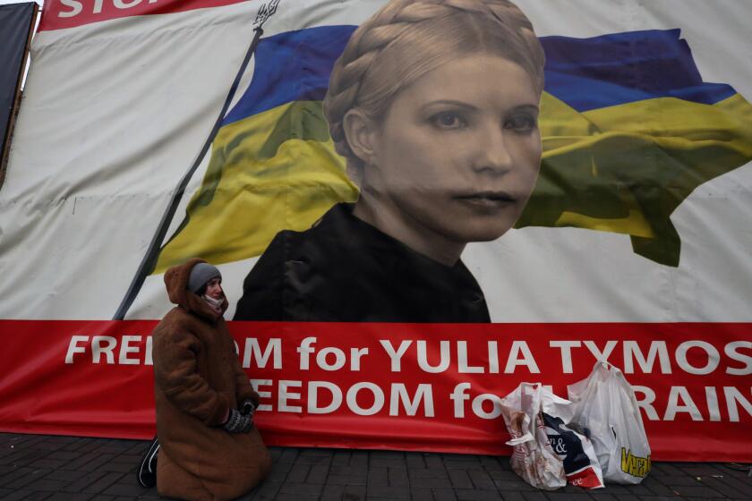 A woman kneels in Independence Square in Kiev, Ukraine, this week in front of a banner showing jailed opposition leader Yulia Tymoshenko.