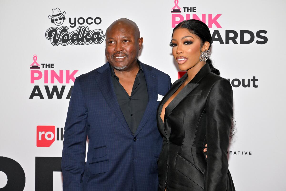 Simon Guobadia and Porsha Williams pose together in dark suits at an awards show