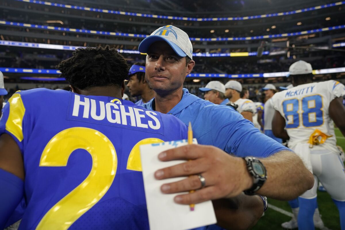 Chargers head coach Brandon Staley, right, hugs  Rams defensive back JuJu Hughes after a preseason game.