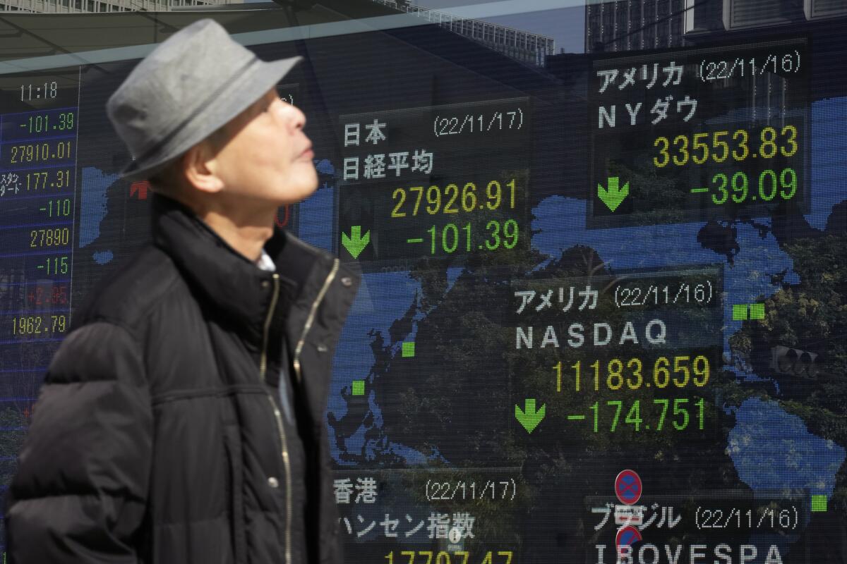 A person walks in front of an electronic stock board showing Japan's Nikkei 225 index.