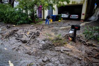 Los Angeles, CA - February 05: A man attempts to sweep mud and debris from the driveway of his Beverly Crest home on N. Beverly Glen Blvd. after an atmospheric river unleashed heavy rain, debris flows, mudslides and flooding in Southern California Monday, Feb. 5, 2024. (Allen J. Schaben / Los Angeles Times)