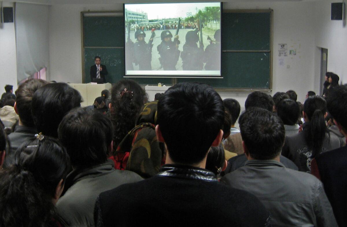 Ilham Tohti speaks at Minzu University in Beijing on Nov. 6, 2009, showing a photo of heavily armed Chinese police facing off with a group of Uighur protesters during July 2009 ethnic violence.