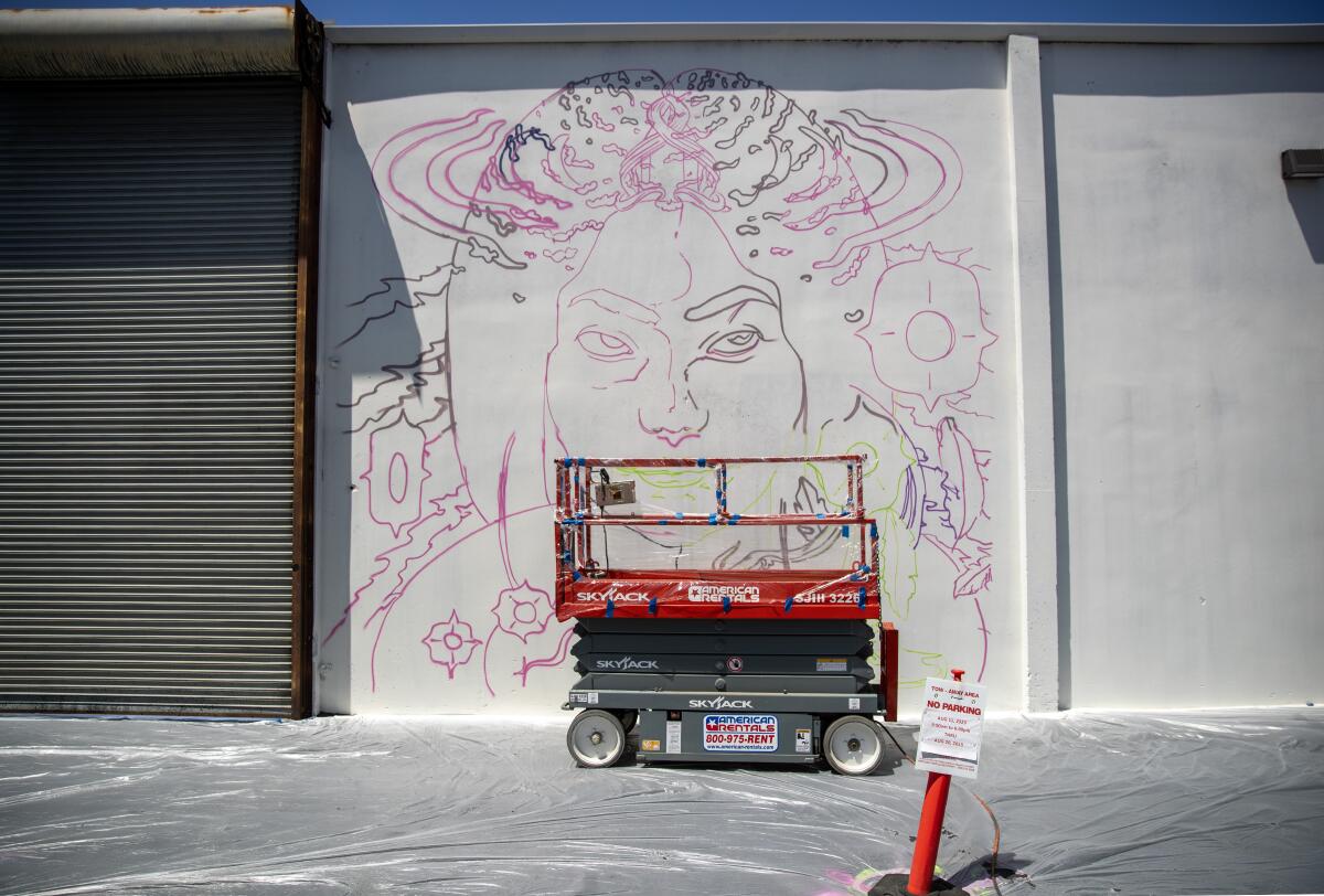 Long Beach Walls artist Roshi's work in progress and an idle scissor lift.