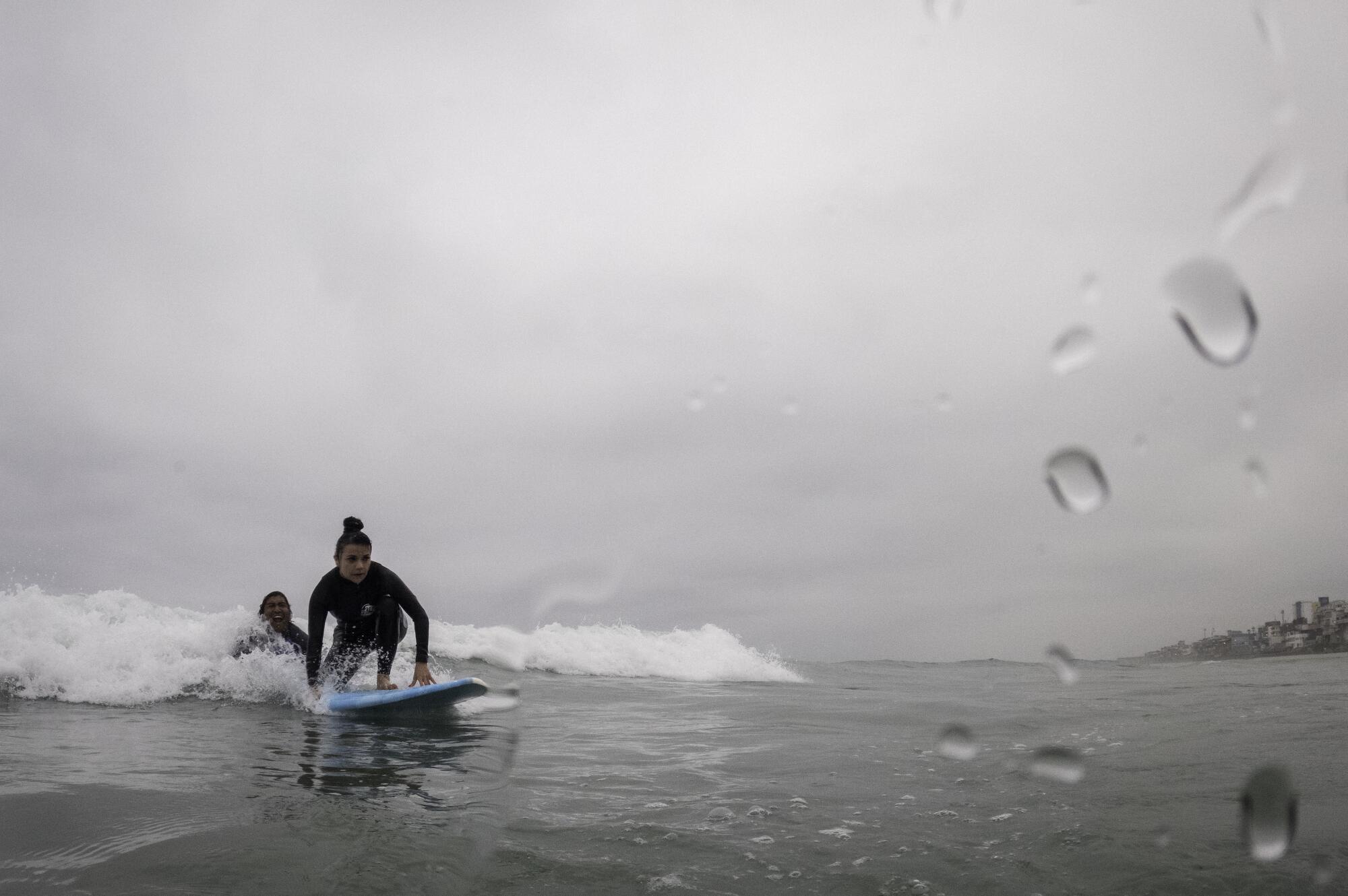 Eliot Hernandez, right, teaches Gabriela Equiz how to surf