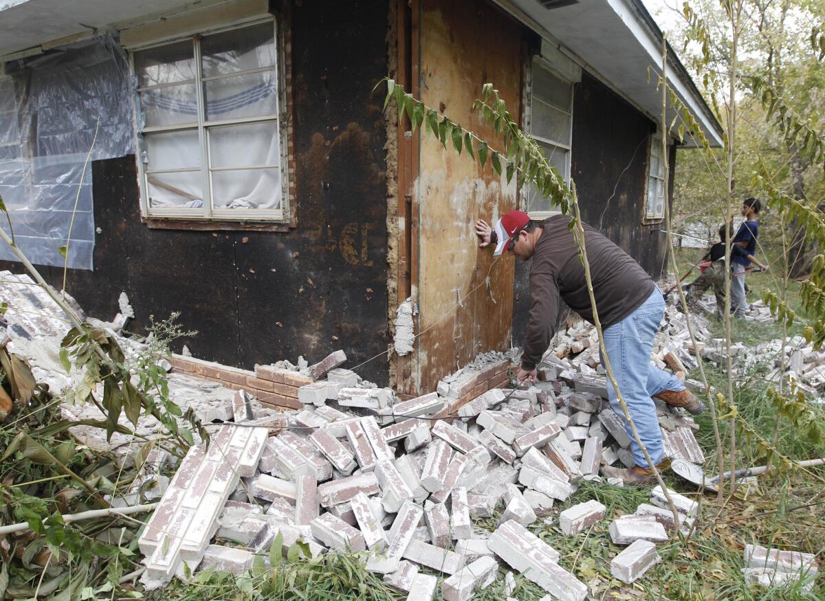 Chad Devereaux examines bricks that fell from three sides of his in-law's home in Sparks, Okla., on Nov. 6, 2011, after two earthquakes hit the area in less than 24 hours. A team of scientists has determined that a 5.6 magnitude quake in Oklahoma in 2011 was caused when oil drilling waste was injected deep underground.
