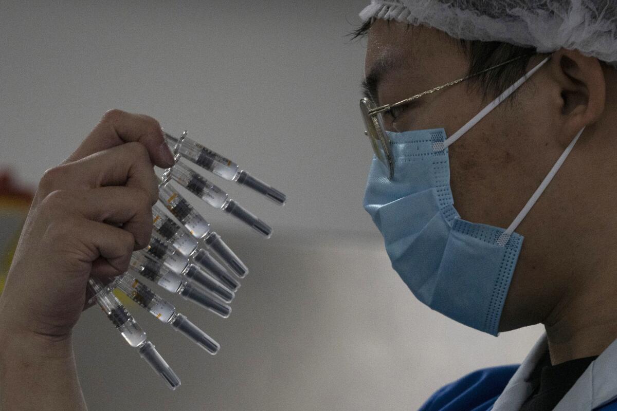 Un trabajador revisa jeringuillas con una vacuna contra el COVID-19 producida por Sinovac.
