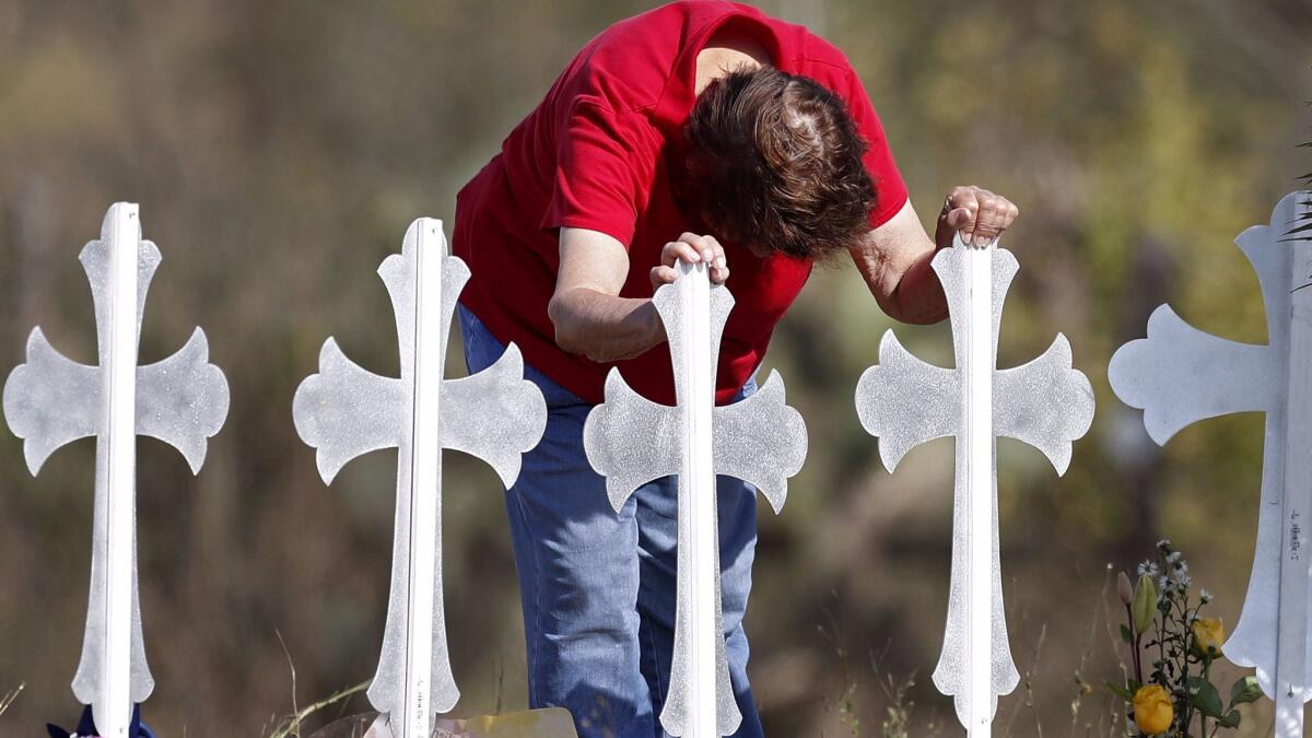 A mourner leans on two of the 26 crosses representing the victims of Sunday's mass shooting in Sutherland Springs, Texas.