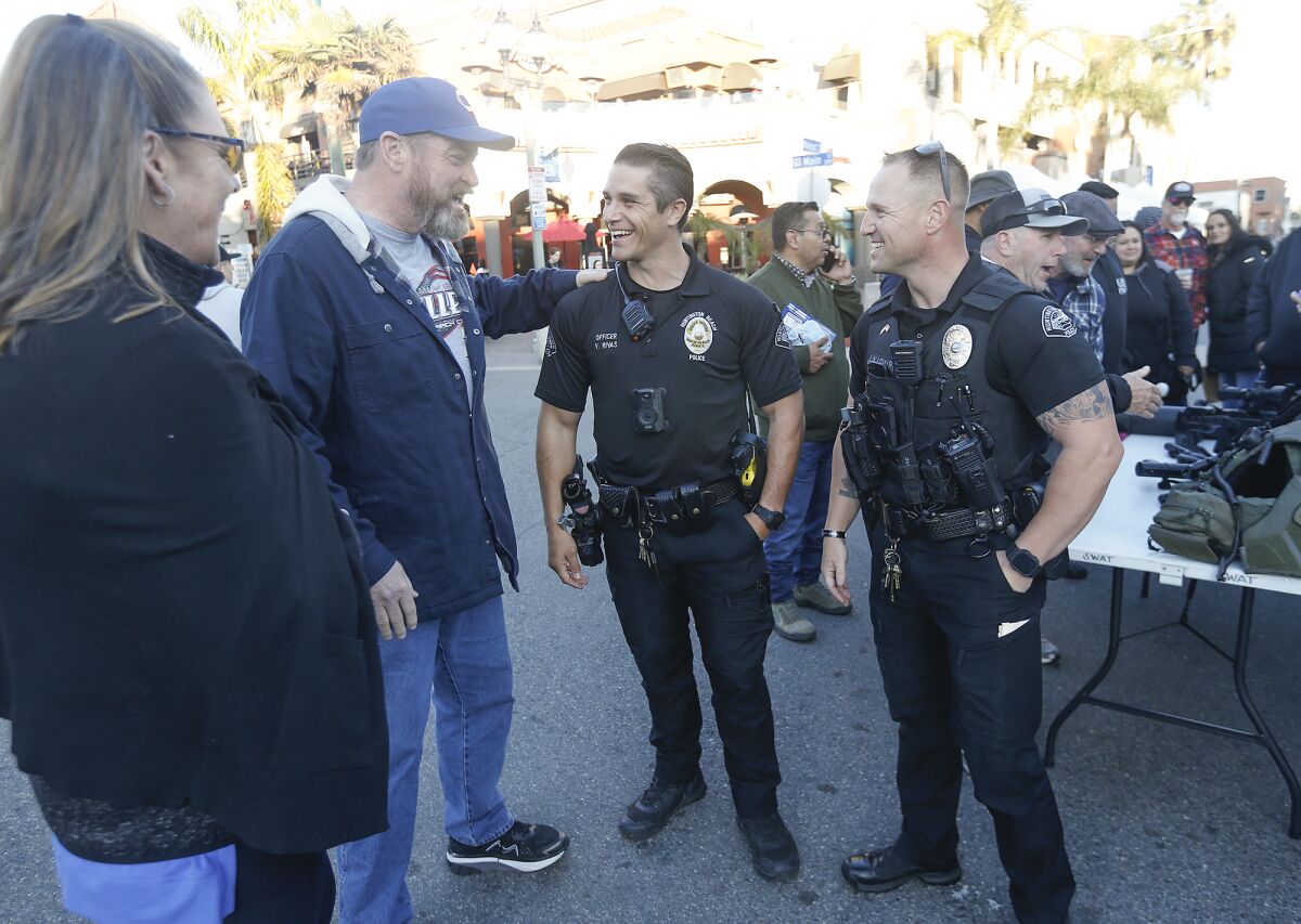 Huntington Beach police officers Vince Rivas and Joe Kasmarski, at right, chat with guests on Tuesday.