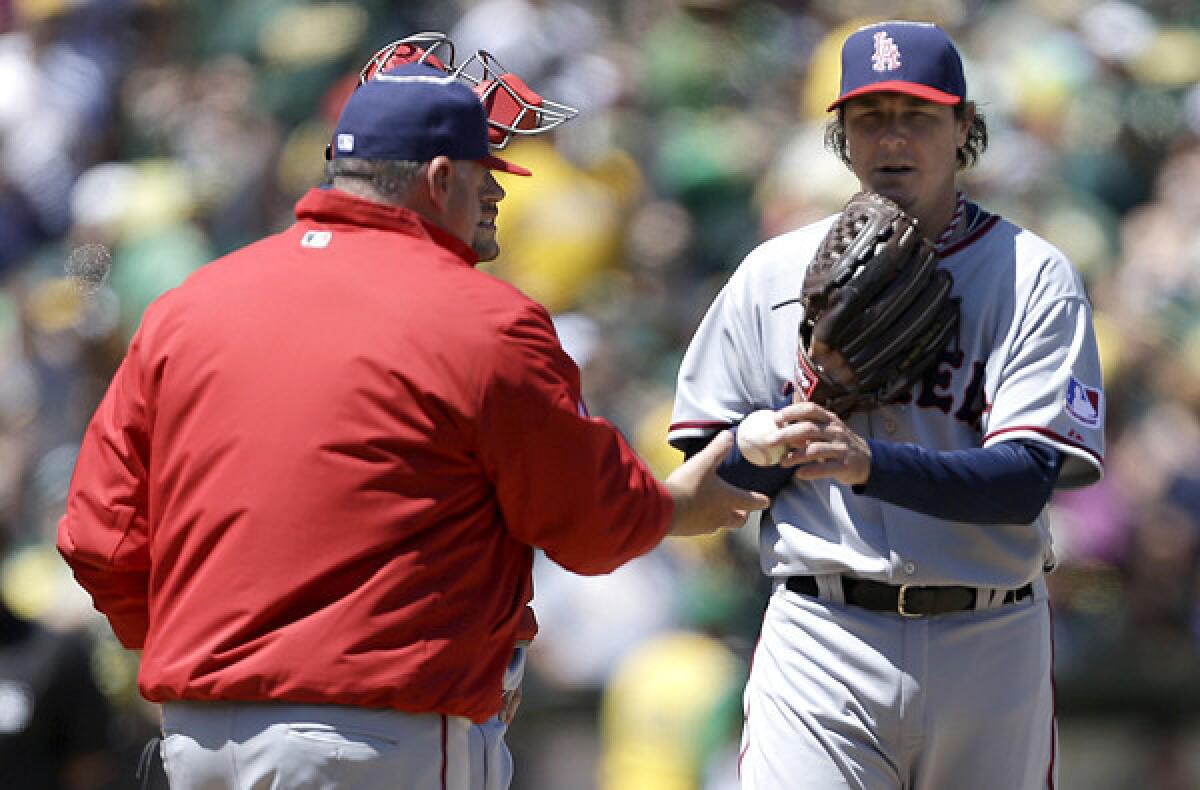 Angels pitcher Scott Downs hands the ball to Manager Mike Scioscia duirng a pitching change in the seventh inning Saturday in Oakland.