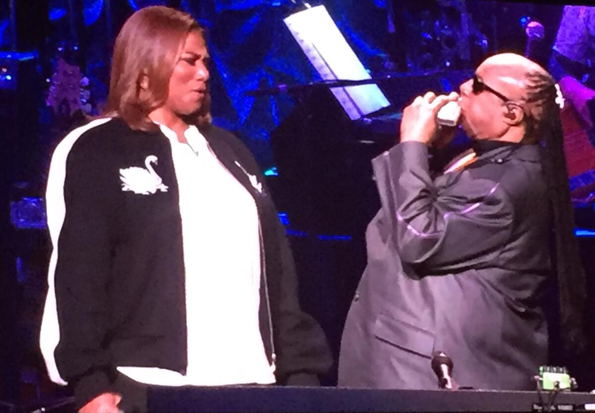 Queen Latifah marvels at Stevie Wonder's harmonica solo during one of her numbers at Wonder's 20th anniversary House Full of Toys benefit concert Friday, Dec. 9, at the Microsoft Theatre in Los Angeles