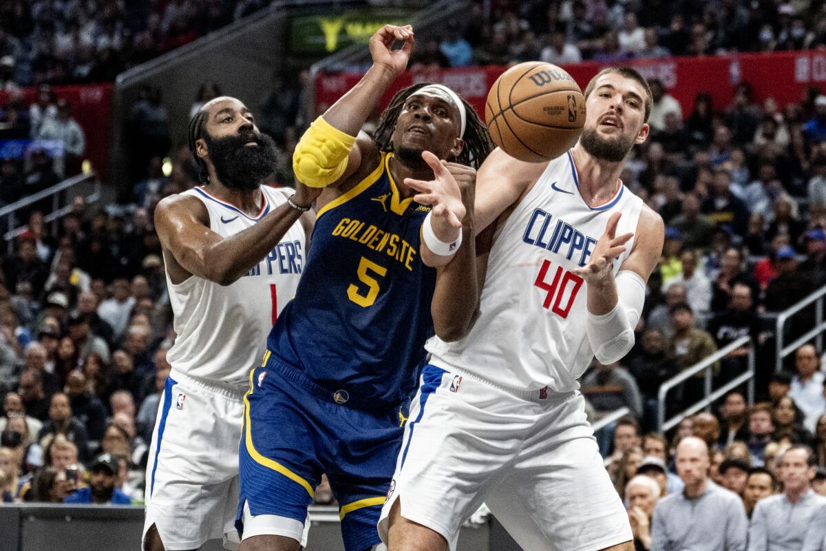 Clippers'ın guardı James Harden ve pivot Ivica Zubac, ribaund için Warriors'ın forveti Kevon Looney ile mücadele ediyor.