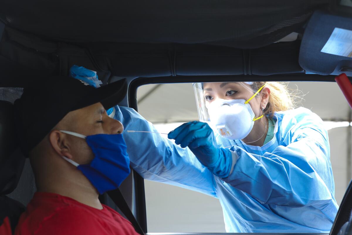 Medical assistant Rhiannon Weik collects a sample with a cotton swab at a recent drive-up testing site.
