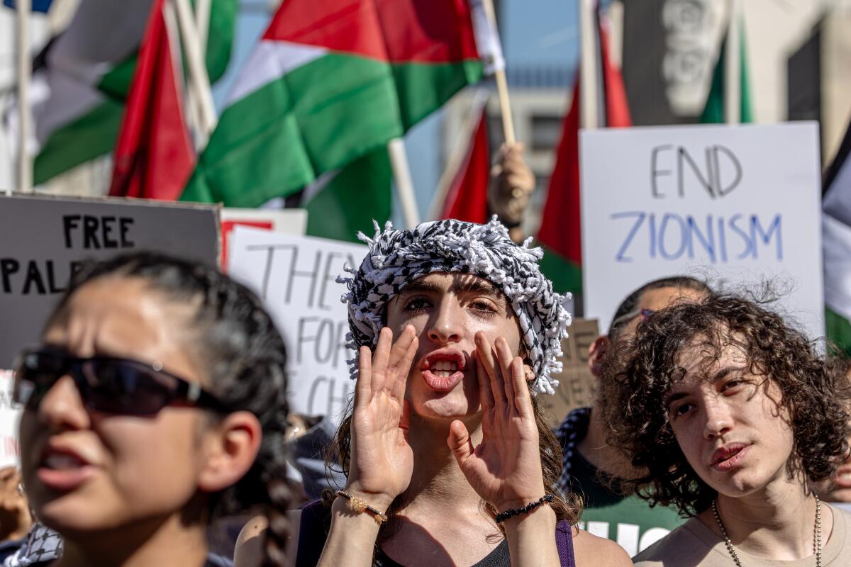 A person in a crowd holds both hands around his mouth and appears to be shouting.