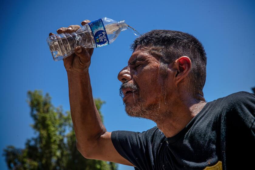 THERMAL, CA - JULY 11: Sergio Lopez, 45, working around his mobile home under blazing sun cools off by pouring cold water over on his head Oasis Mobil Home Park on Tuesday, July 11, 2023 in Thermal, CA. (Irfan Khan / Los Angeles Times)