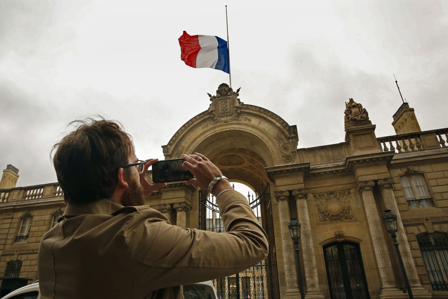 Sylvain Perriot stops to take a picture of the flag at half mast above the Presidential Palace in Paris. France's Sate of Emergency will continue, with flags at half mast.