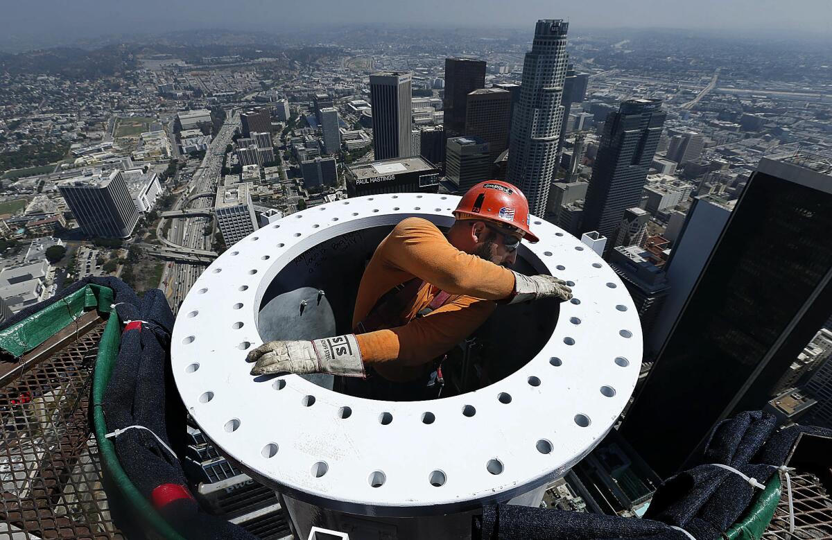 Ironworker Eric Madrigal makes preparations for the final section of a spire rising above the Wilshire Grand in Los Angeles.