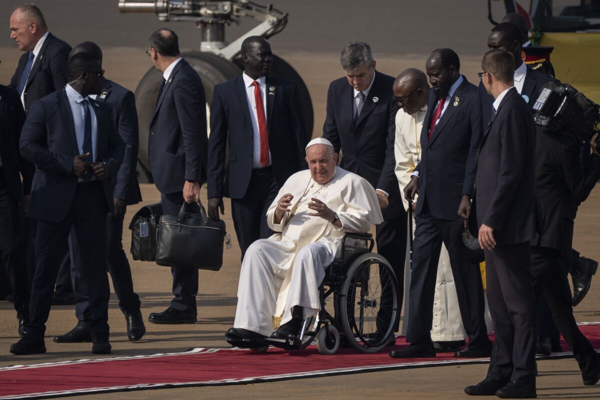 Pope Francis talks to South Sudan's President Salva Kiir, center-right, after arriving at the airport in Juba, South Sudan Friday, Feb. 3, 2023. Pope Francis arrived in South Sudan on the second leg of a six-day trip that started in Congo, hoping to bring comfort and encouragement to two countries that have been riven by poverty, conflicts and what he calls a "colonialist mentality" that has exploited Africa for centuries. (AP Photo/Ben Curtis)