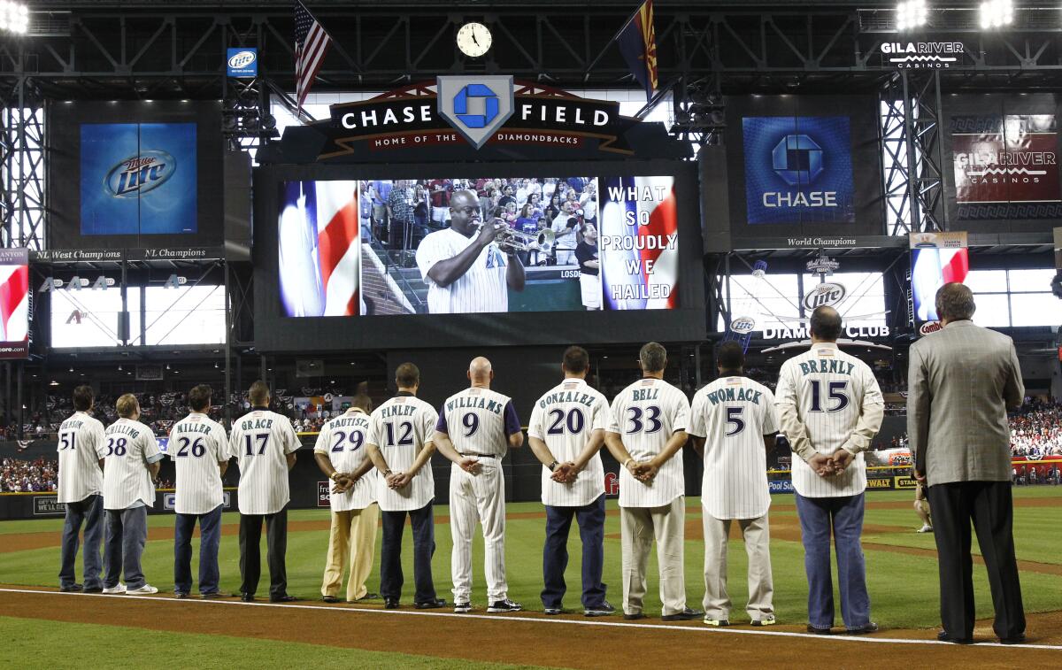 Members of the 2001 Arizona Diamondbacks watch a trumpet player on the big screen. 