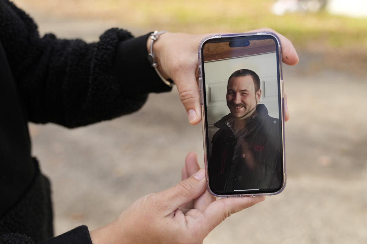A woman shows a picture of a man on a cellphone.