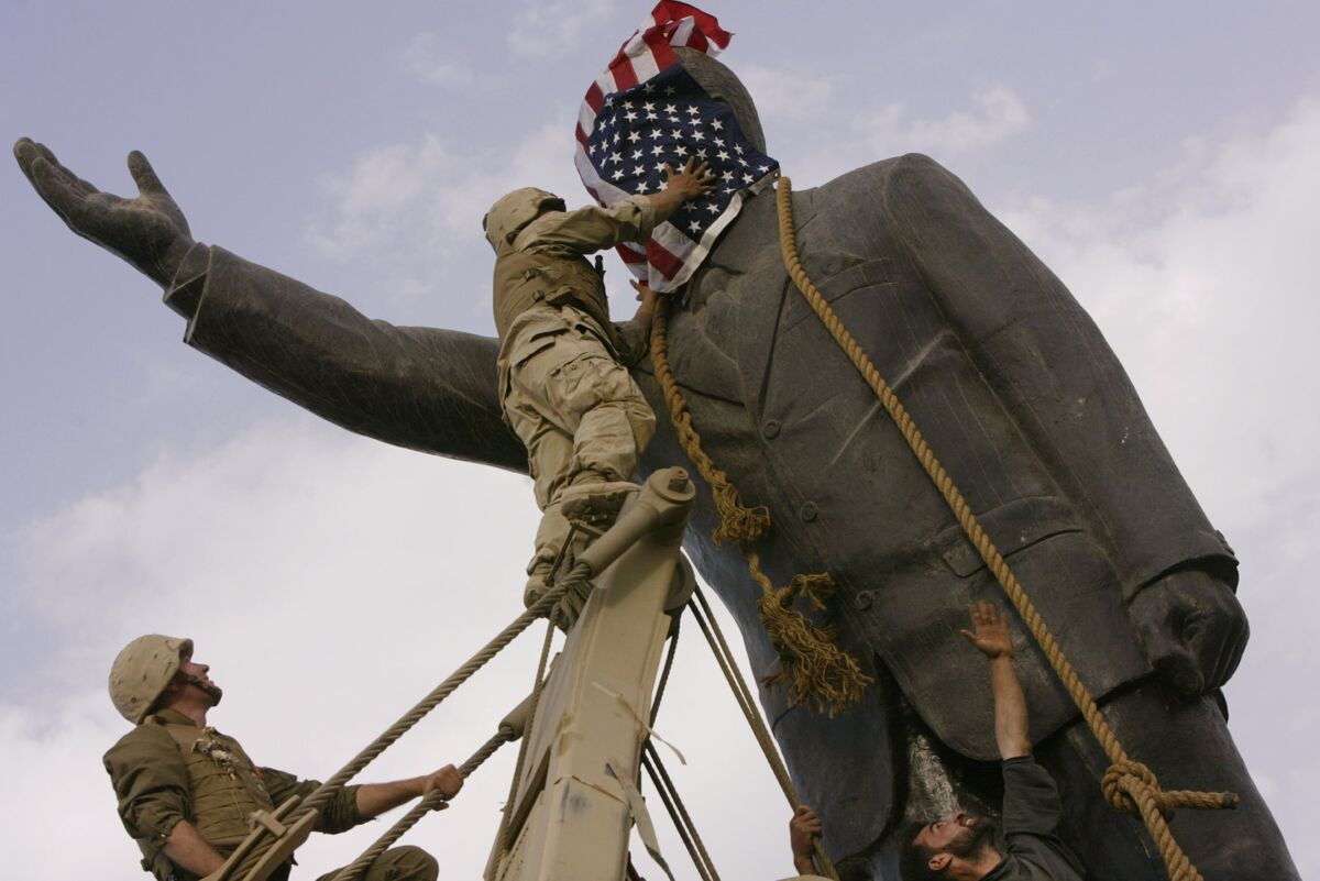FILE - Cpl. Edward Chin of the 3rd Battalion, 4th Marines Regiment, covers the face of a statue of Saddam Hussein with an American flag before toppling the statue in downtown Baghdad, Iraq, on April 9, 2003. Congress is now considering doing something it hasn't done since the Vietnam War - repealing authorizations for the use of military force and thus reclaiming its say over the wars America wages abroad. The Senate voted 66-33 on March 29, 2023, to repeal the 2002 resolution giving President George W. Bush the green light to invade Iraq. (AP Photo/Jerome Delay, File)