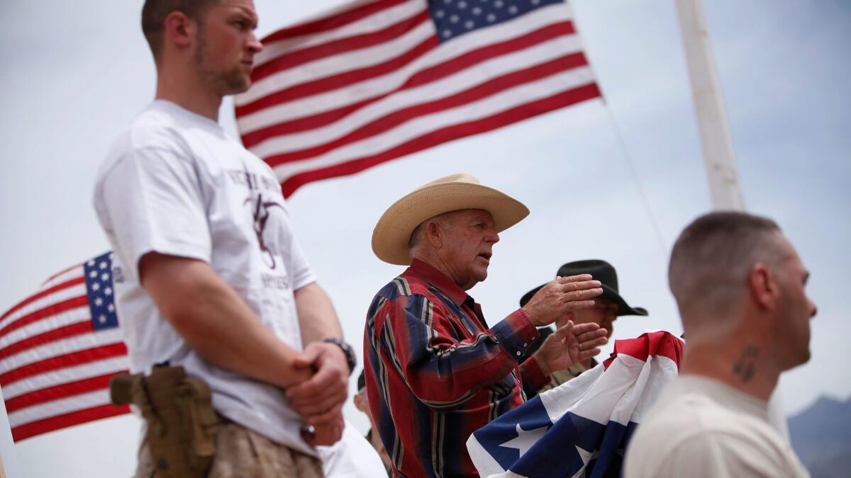 Rancher Cliven Bundy, flanked by armed supporters in April 2014, speaks at a protest camp near Bunkerville, Nev.