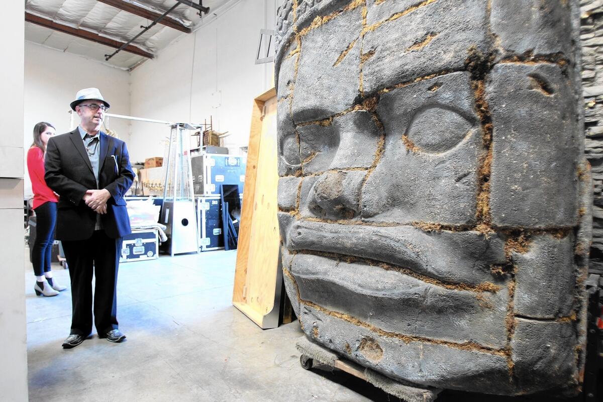 Robert Bates, vice president of sales and business development, stands next to one of hundreds of props, in this case a wall-sized replica of the Cambodian Smiling Faces of Bayon, inside the BTB Event Production warehouse in Costa Mesa.