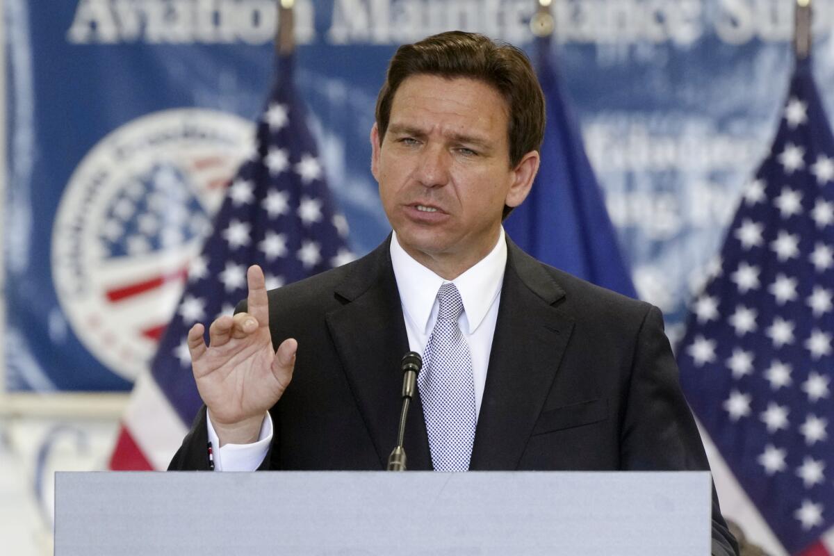 Florida Gov. Ron DeSantis, wearing a dark suit, white shirt and lavender tie