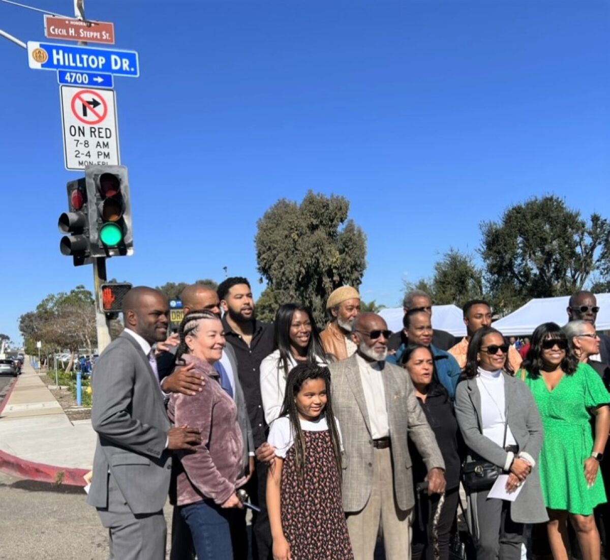 Cecil Steppe, 90, front row center, is joined by family and friends in front of his honorary street sign by Gompers Academy.