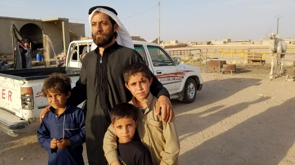Sheikh Fawaz Beik stands with three of his sons outside his house in Mansoura, where he was attacked the week before, his truck marred by debris from the explosion that injured two relatives and one of his camels.
