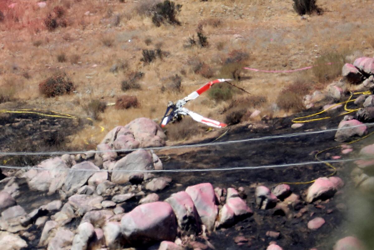 Twisted helicopter blades lay among a scorched earth and boulders stained pink by fire retardant.