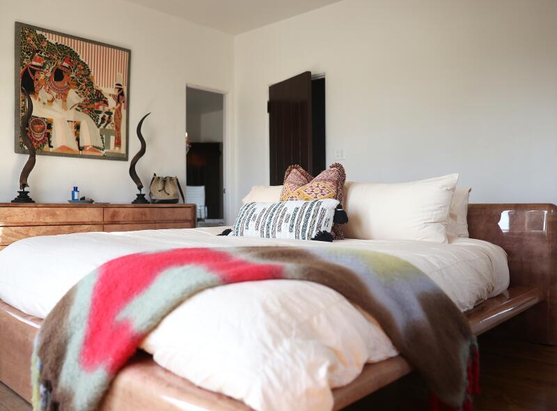 A platform bed with a colorful blanket in a room in beiges and brown