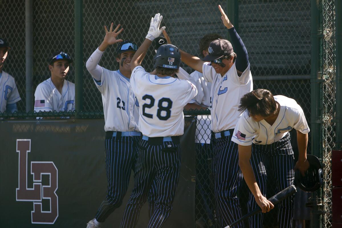 Corona del Mar's Dennis Fitzpatrick (28) is congratulated by teammates after he scores the first run against Laguna Beach.  