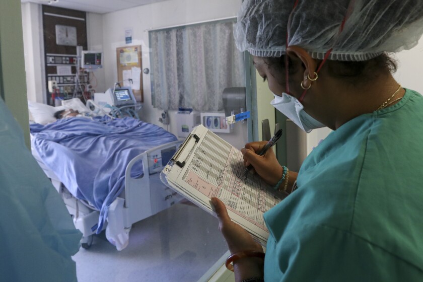 Nurse Kyah Paschall takes notes on a COVID-19 patient at Paradise Valley Hospital in National City.