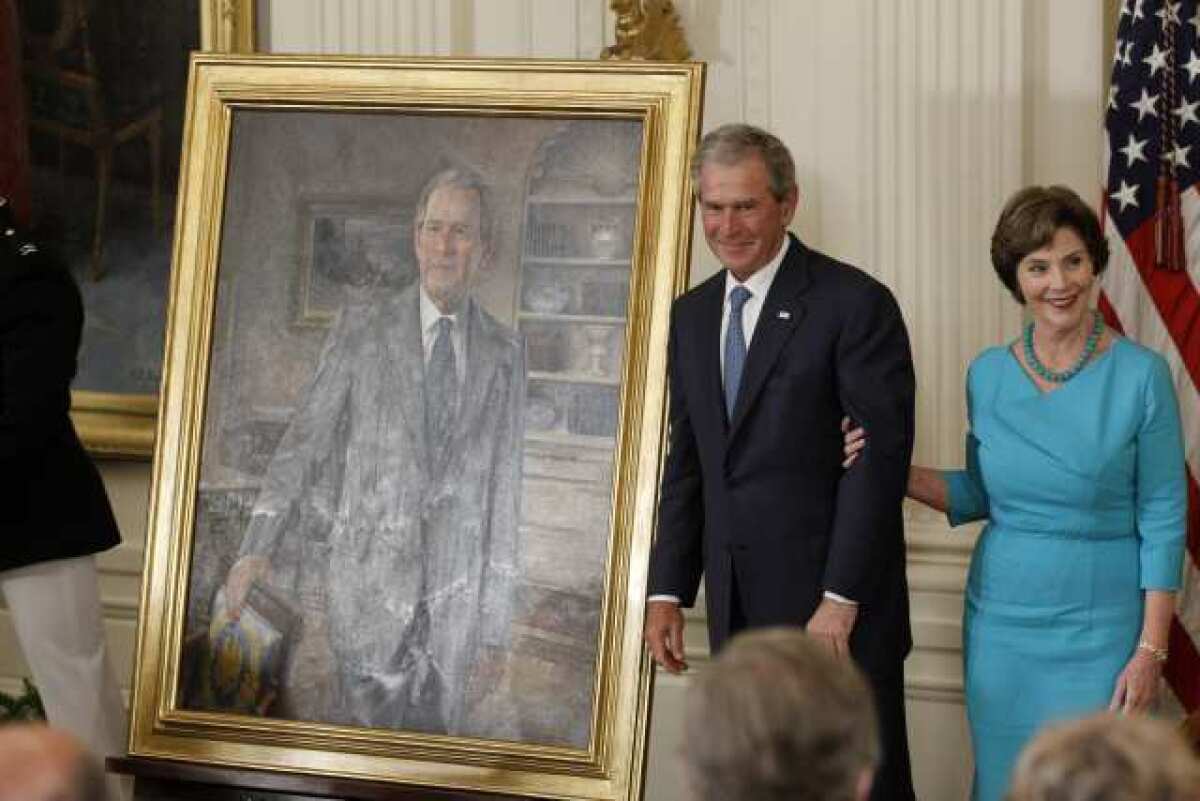Former President George W. Bush and his wife, Laura, stand next to his portrait during an unveiling ceremony at the White House.