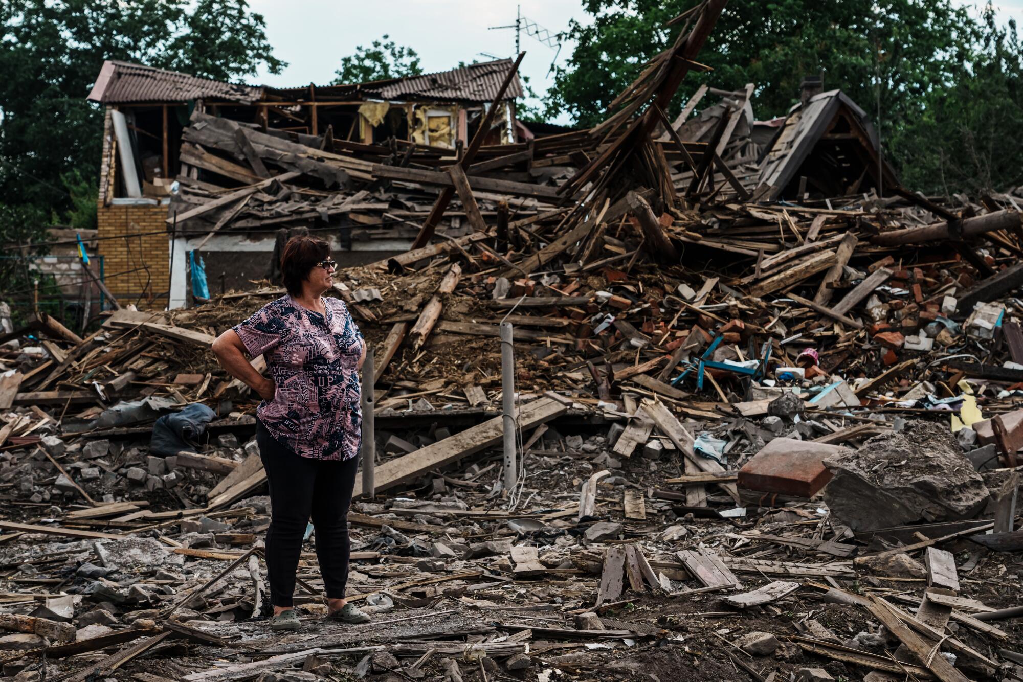 A woman looks on after a home is destroyed by a bombardment that hit a neighborhood in Dobropillya, Ukraine.