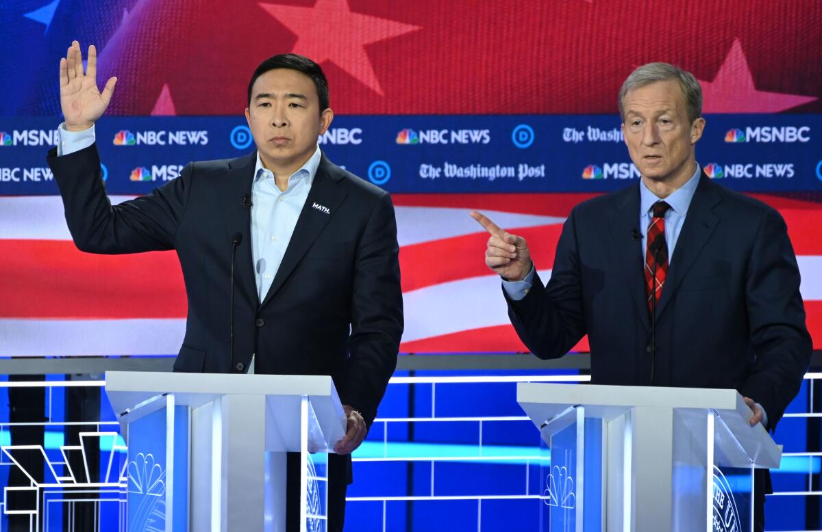 Andrew Yang motions on Nov. 20 debate stage while Tom Steyer speaks.