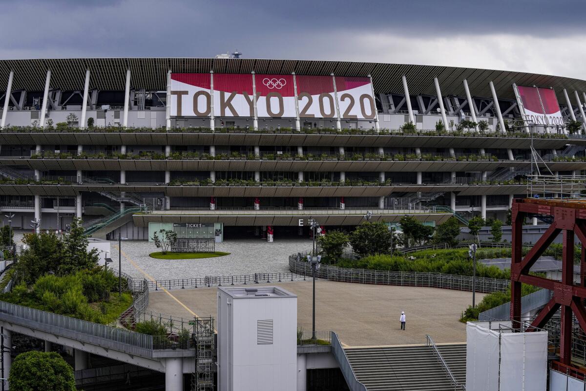 Un empleado camina frente al Estadio Nacional de Tokio, el miércoles 23 de junio de 2021.