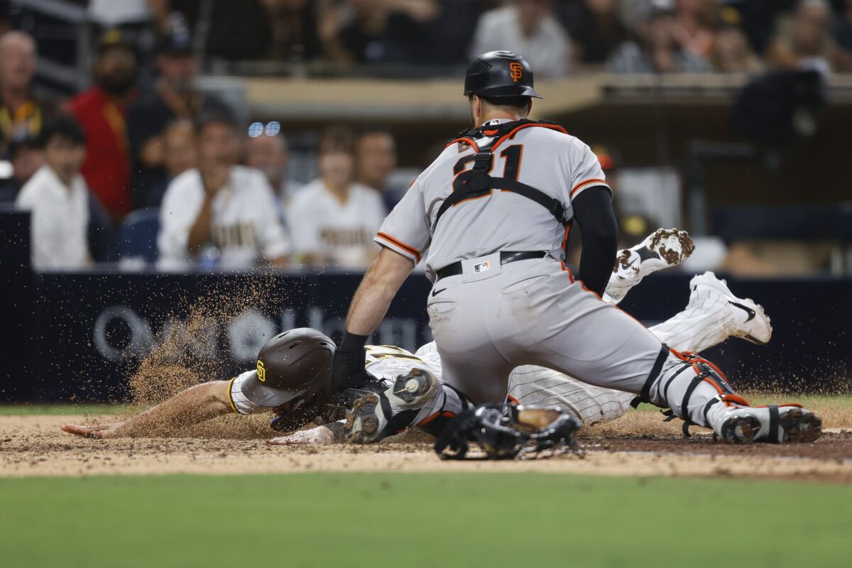 San Diego Padres' Brandon Drury, left, is tagged out at the plate by San Francisco Giants catcher Joey Bart during the eighth inning of a baseball game, Monday, Aug. 8, 2022, in San Diego. (AP Photo/Mike McGinnis)