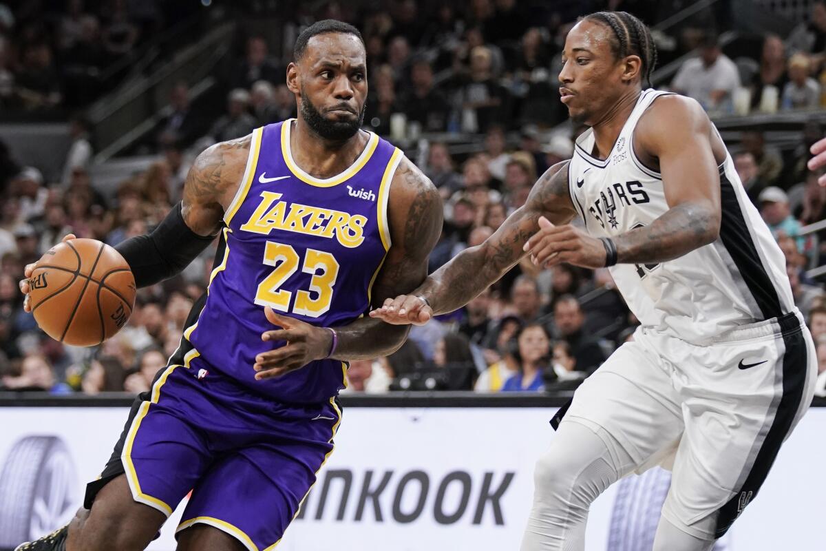 Lakers star LeBron James, left, drives against San Antonio Spurs forward DeMar DeRozan during the first half Sunday.