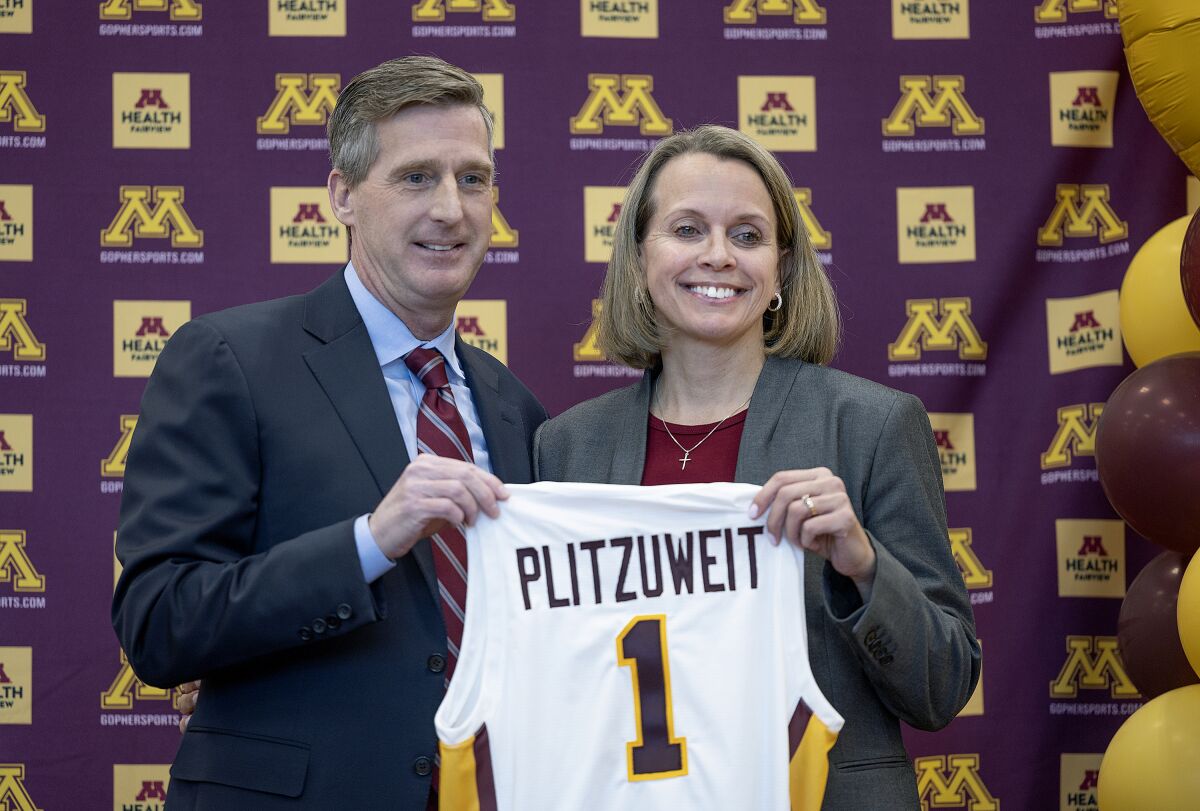 University of Minnesota Athletic Director Mark Coyle, left, introduces Dawn Plitzuweit, the schools new women's NCAA college basketball head coach, during a press conference in Minneapolis, Monday, March 20, 2023. (Elizabeth Flores/Star Tribune via AP)