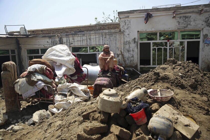 An Afghan man sits amid the belongings from his house that was damaged by a mudslide, in Parwan province, north of Kabul, Afghanistan, Thursday, Aug. 27, 2020. The death toll from heavy flooding in northern and eastern Afghanistan rose to at least 150 on Thursday, with scores more injured as rescue crews searched for survivors beneath the mud and rubble of collapsed houses, officials said. (AP Photo/Rahmat Gul)
