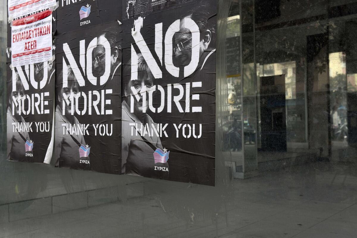 Posters showing German Chancellor Angela Merkel and former Greek Prime Minister Antonis Samaras and reading "No More" are pasted on the window of a closed car dealership in Athens on Feb. 11.