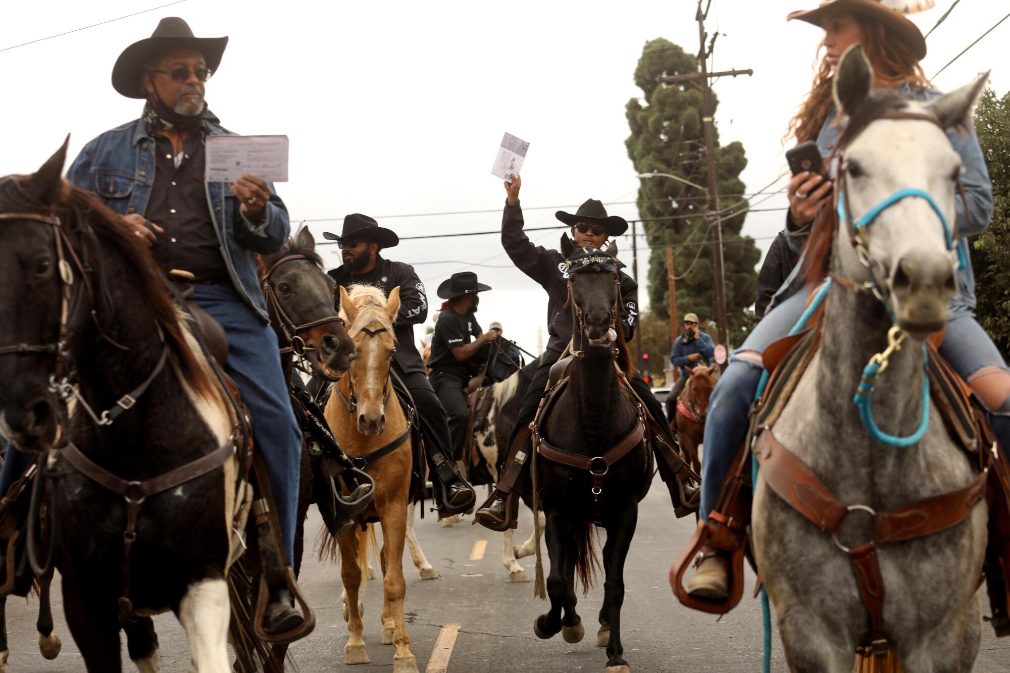 The Compton Cowboys ride through town to deposit their ballots in a drop box at the Compton Library on Sunday.