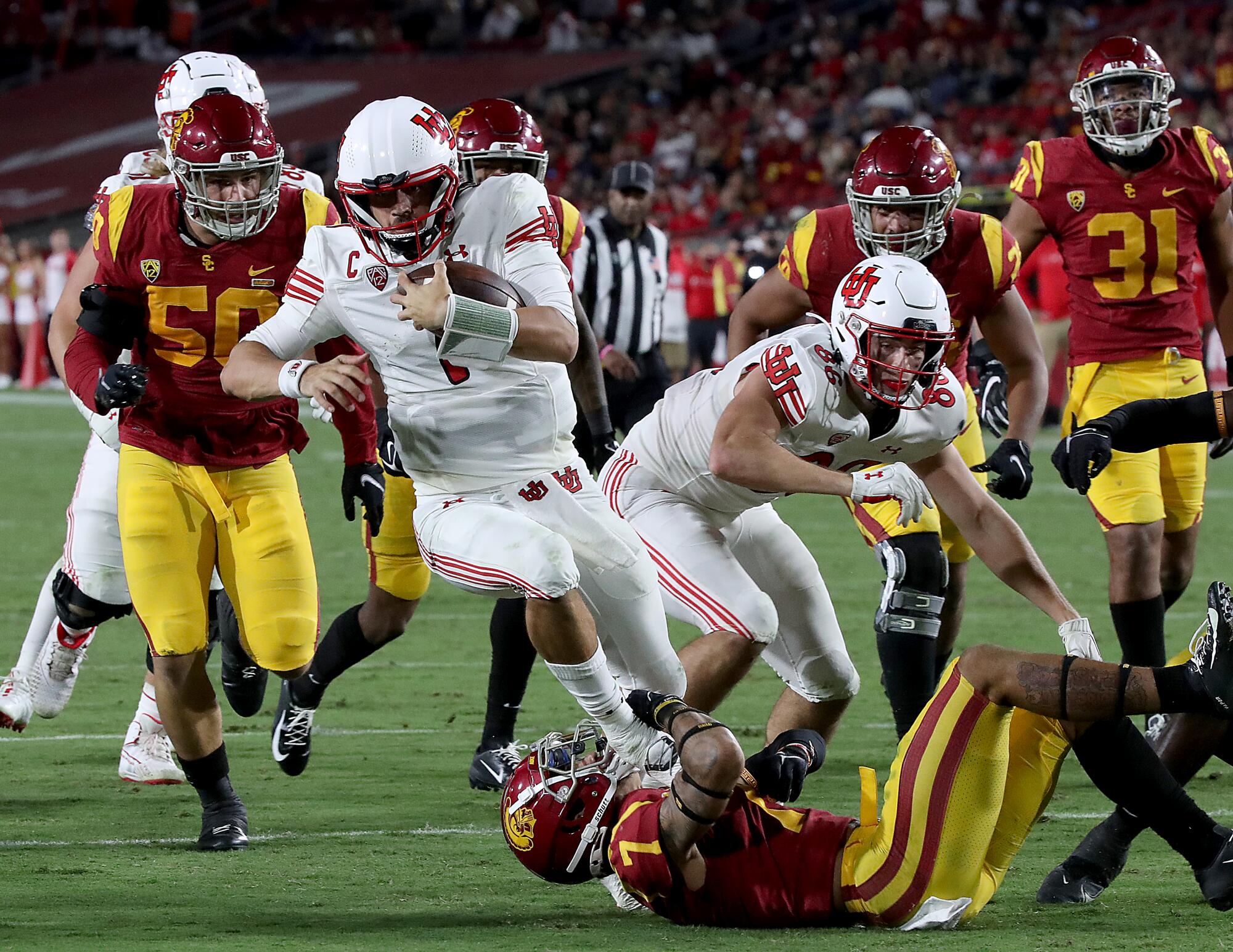 Utah quarterback Cameron Rising runs over USC strong safety Chase Williams  on his way to scoring a touchdown.