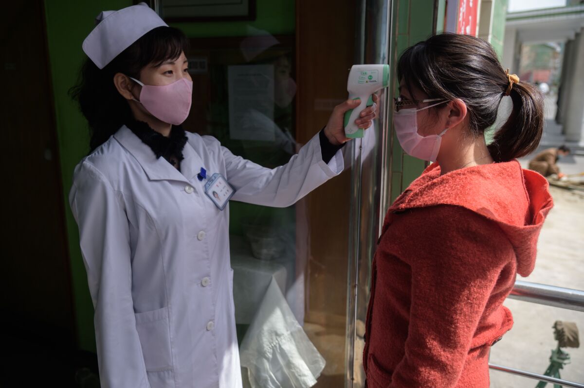 A health worker takes a woman's temperature at an entrance of the Pyongchon District People's Hospital in Pyongyang.