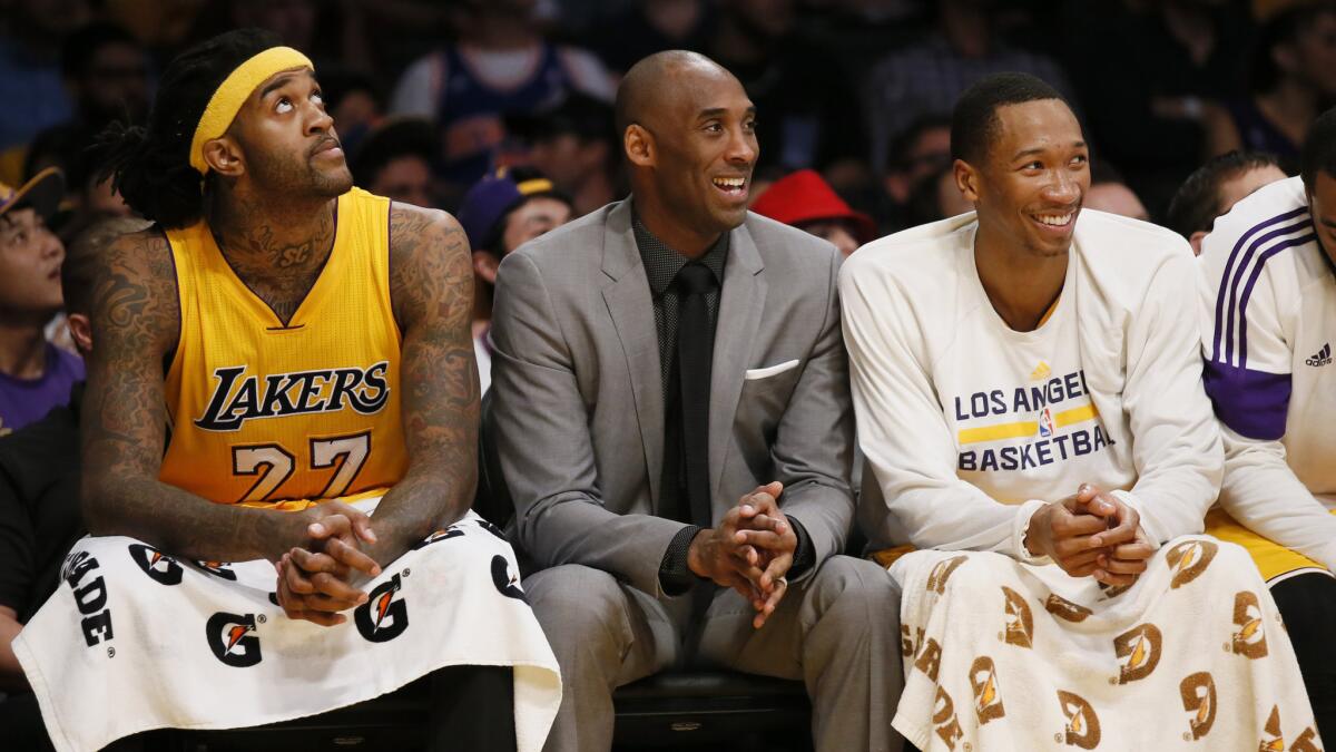 Injured Lakers star Kobe Bryant, center, laughs while sitting on the bench between teammates Jordan Hill, left, and Wesley Johnson during a loss to the New York Knicks on Thursday.
