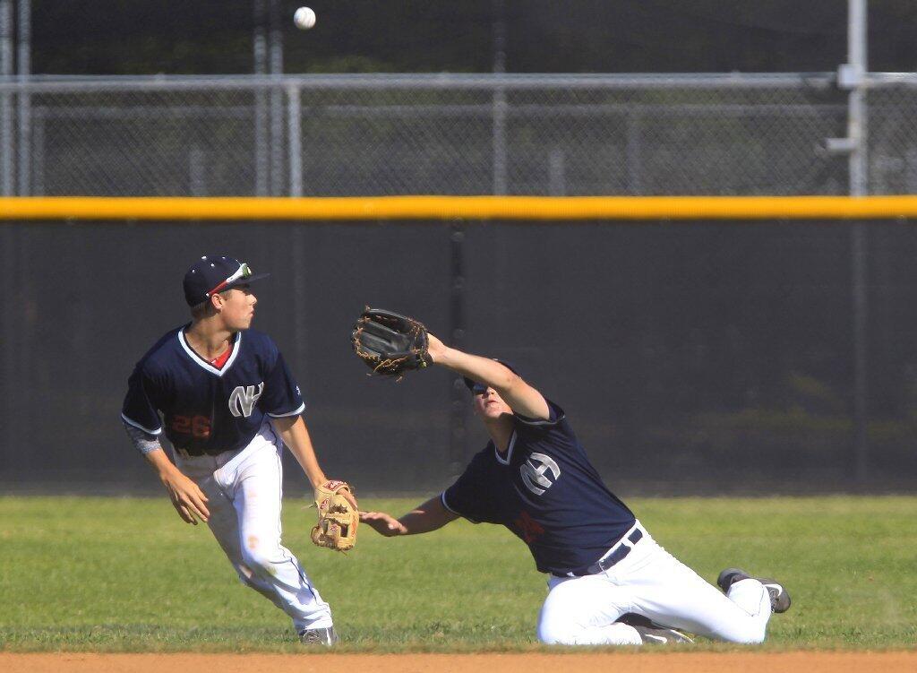 Newport Harbor High's Cameron Jabara, left, looks on as teammate Rigsby Duncan attempts to make a play on the ball during the fourth inning against Huntington Beach in a Sunset League game on Tuesday.