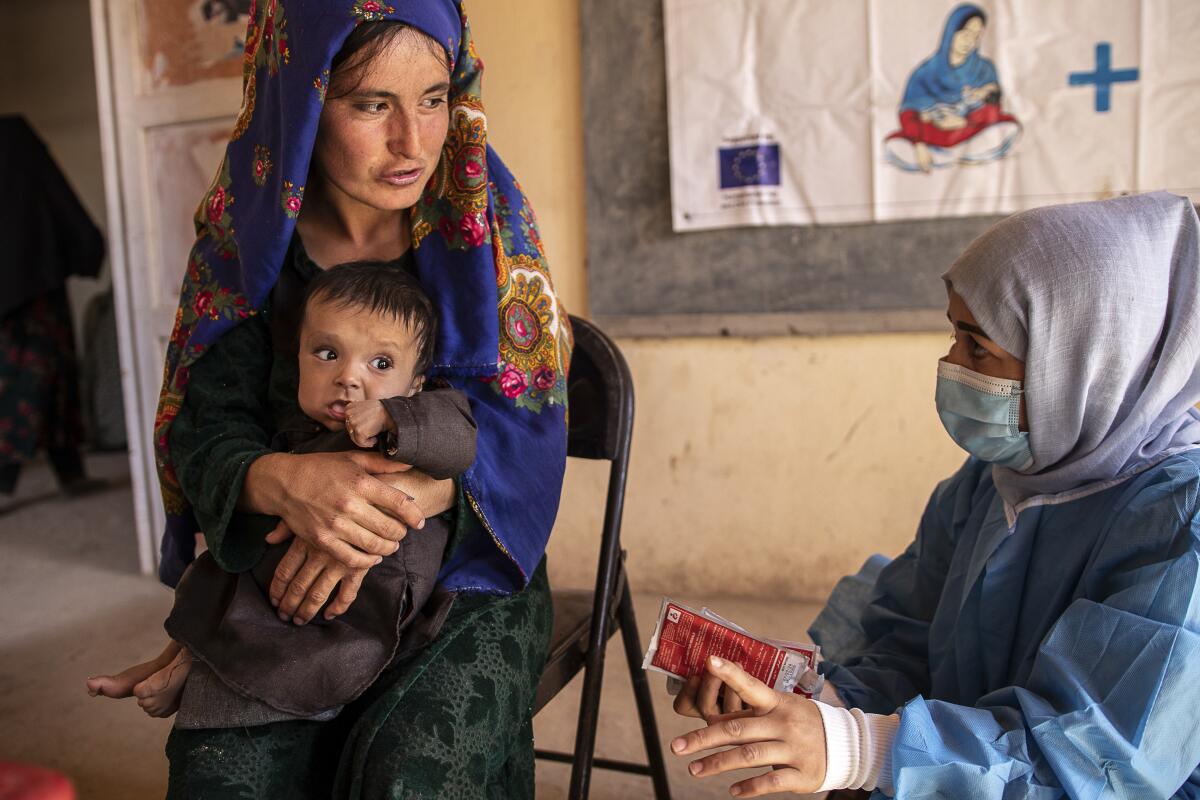 Afghan woman with her child, speaking to an aid worker
